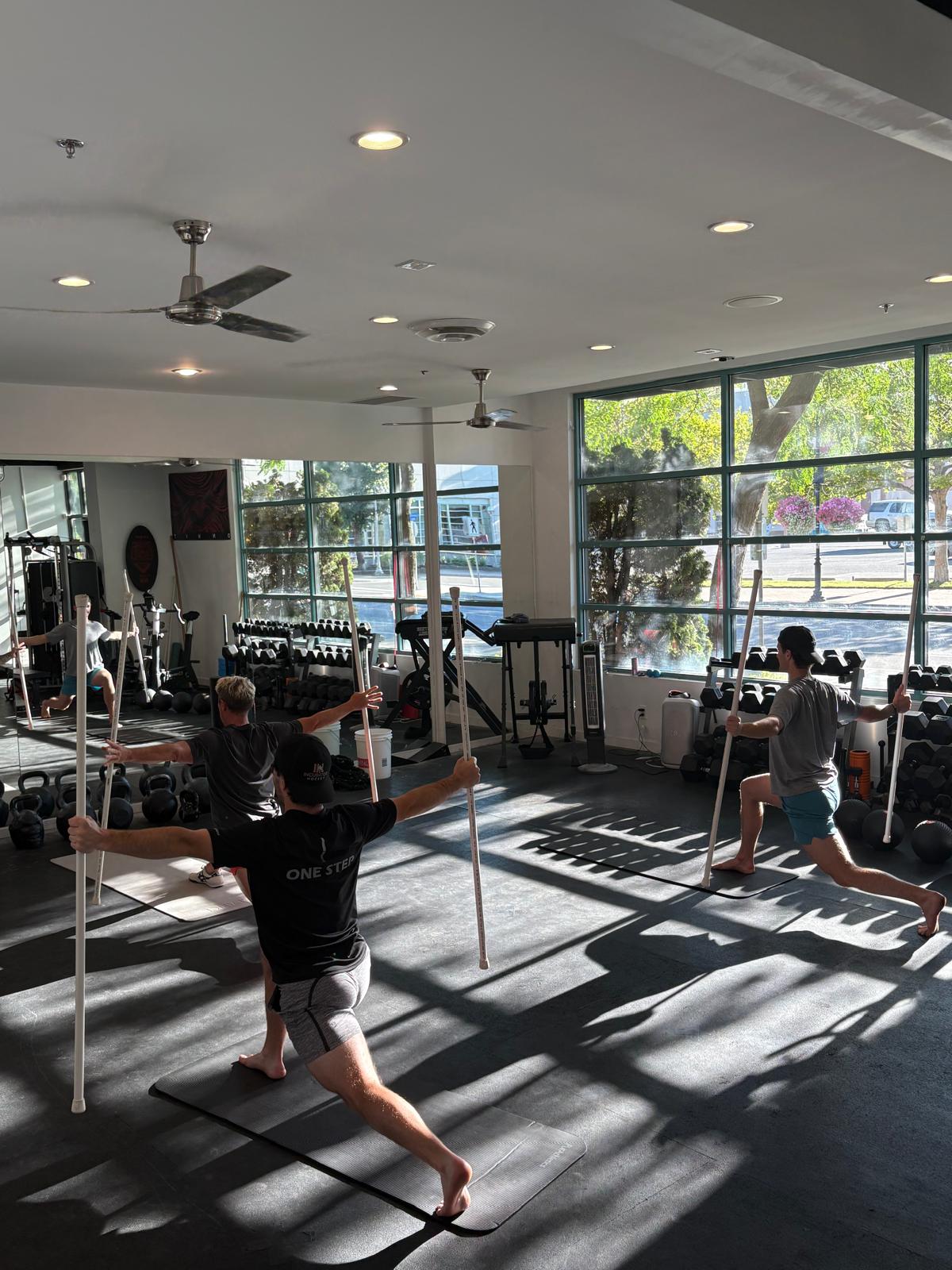 Athletes training mobility with poles in a Hood Athletic Edge class
